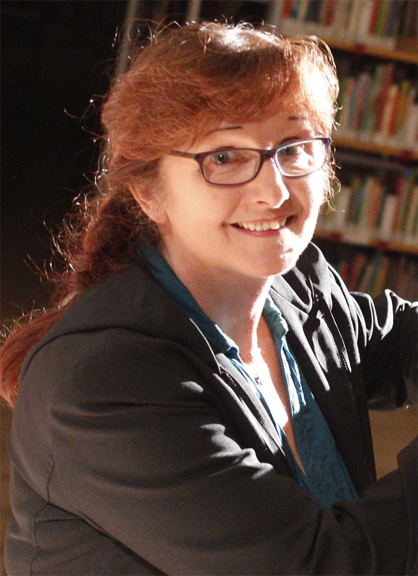 Elke Büchner seitlich vor einem Bücherregel. Foto: von M.Bauroth