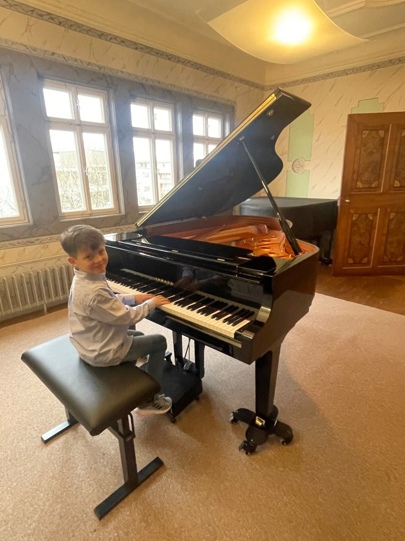 Justus Schneider sitzt in einem Raum vor einem Klavier